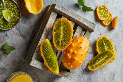 Sliced and whole kiwano fruit laying in a wooden basket