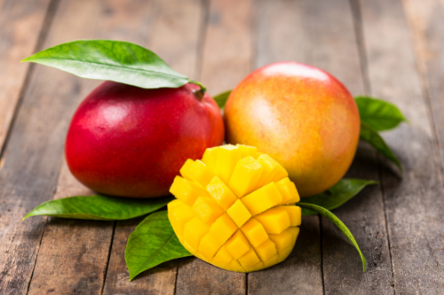 Mangos laying on leaves on a wooden table