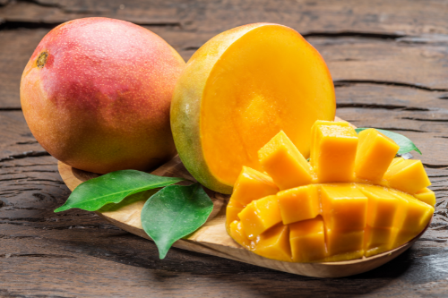 Mangos laying on leaves on a wooden table