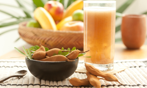 Exotic tamarind smoothie in a glass next to a bowl with tamarind fruit